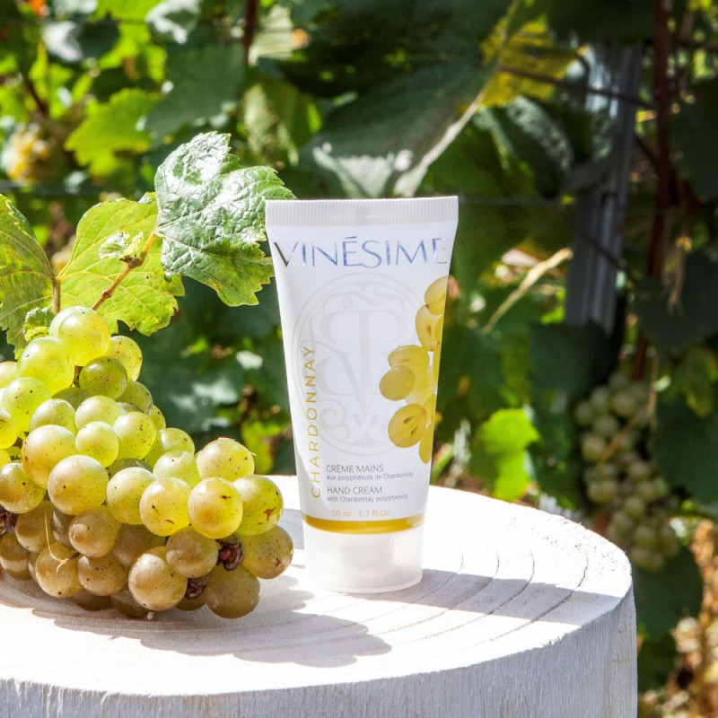 Crème Mains Chardonnay vinesime avec grappe de raisins chardonnay sur support en bois devant vigne bourgogne